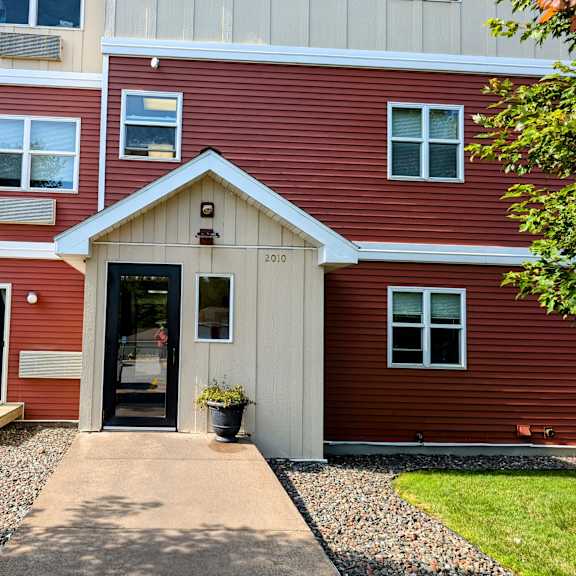 the front entrance of a red house with a porch
