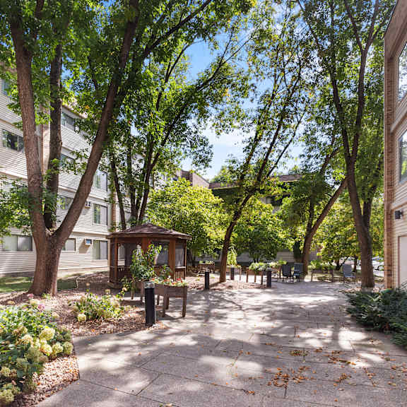 a tree-lined walkway leads to a small pavilion in a courtyard.