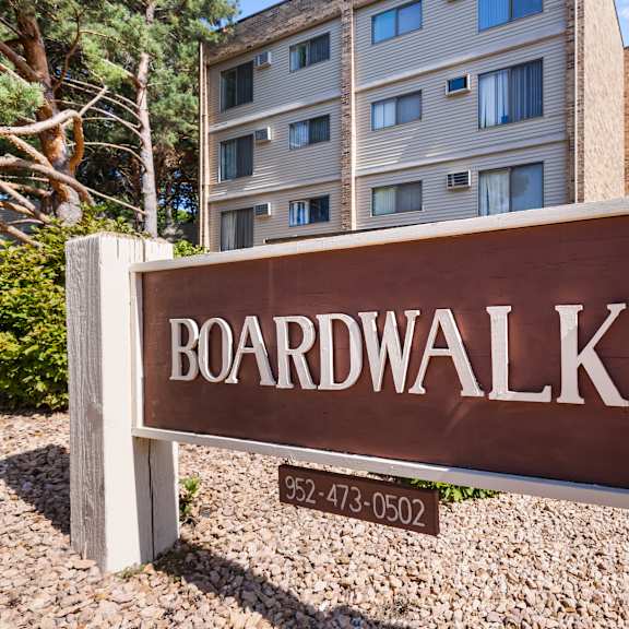 a brown sign that says boardwalk in front of a building.