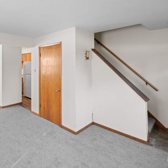 a room with a grey carpet and a wooden door.