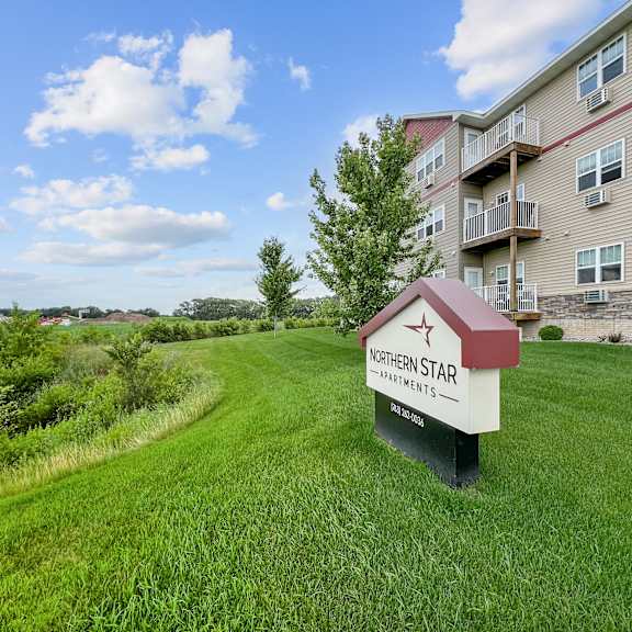 a sign for northern star apartments stands in a grassy field.