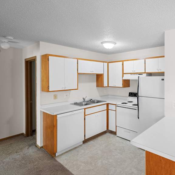 an empty kitchen with white appliances and wooden cabinets