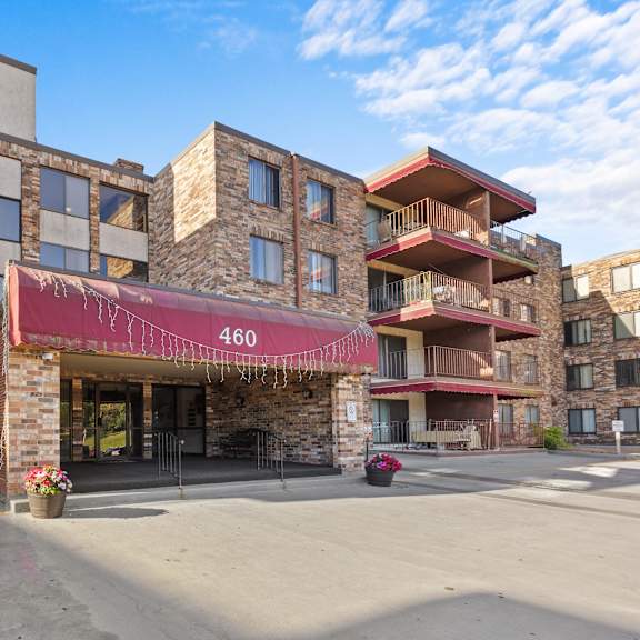 an apartment building with a red awning and a street in front