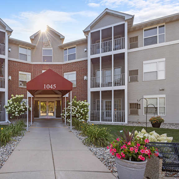 an exterior view of an apartment building with a walkway and flowers