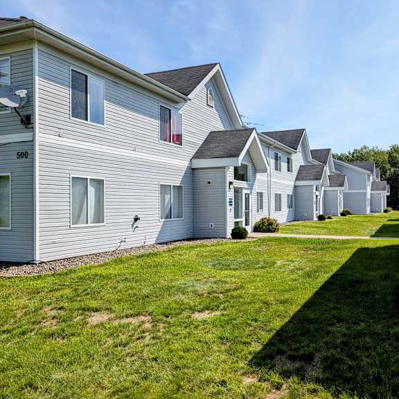 a row of white houses on a green lawn