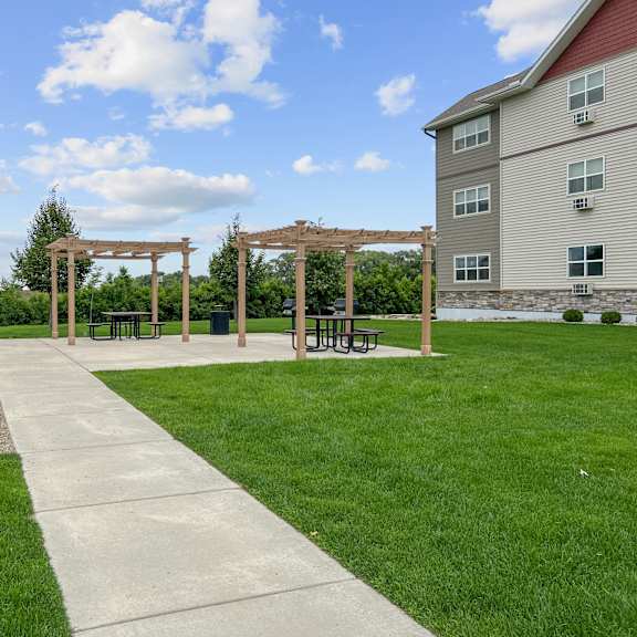 a park with a walkway, benches, and a wooden structure.