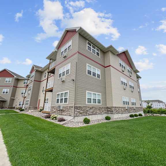 a large apartment building with a red roof and a green lawn in front.