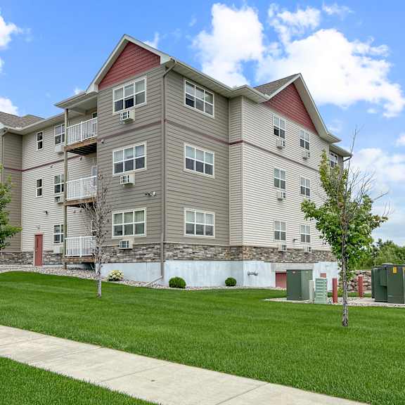 a large apartment building with a red roof and a tree in front.
