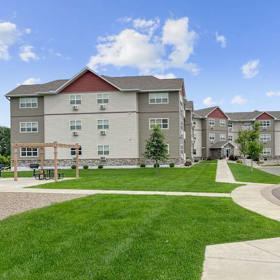 a large apartment complex with a grassy courtyard and a walking path.