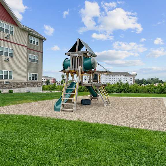 a playground with a green slide and a wooden ladder.