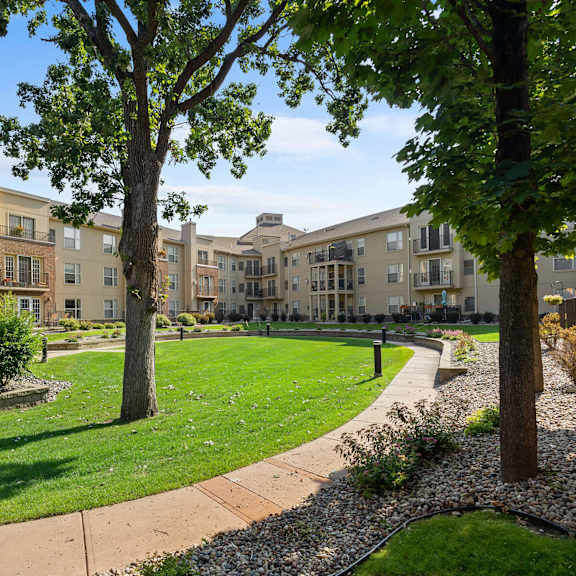 a park with trees and grass in front of an apartment building