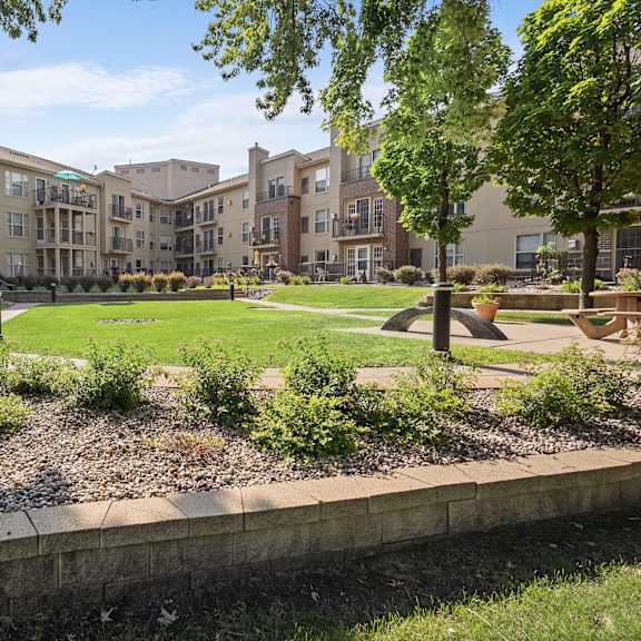 a courtyard with trees and grass in front of an apartment building