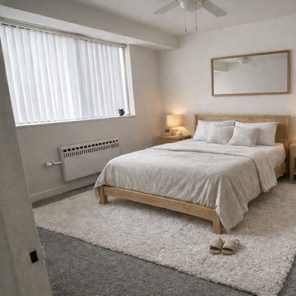 a bedroom with a large bed, a ceiling fan, and a window with blinds.
