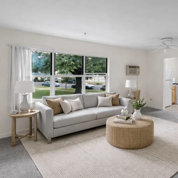 a living room with a grey couch, a round wicker table, and a grey rug.