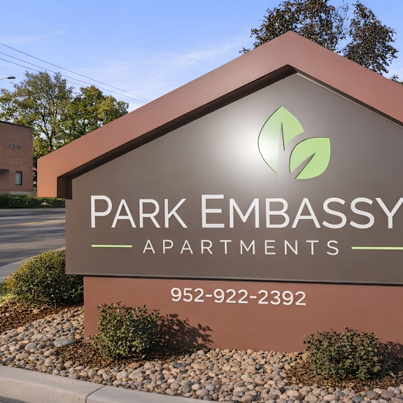 a sign for park embassy apartments with a phone number on it.