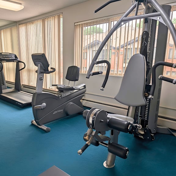 a gym with a variety of equipment including treadmills, stationary bikes, and weight machines.