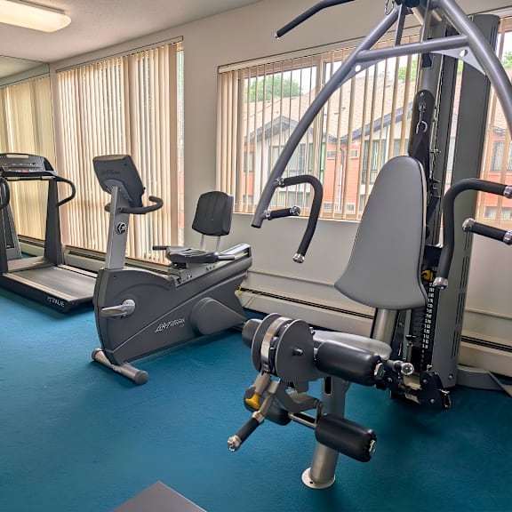 a gym with a variety of equipment including treadmills, elliptical machines, and weight machines.
