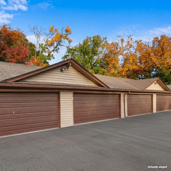 a house with a brown garage door in front of a tree with autumn leaves.