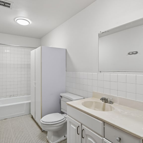 a white bathroom with a toilet, sink, and bathtub.