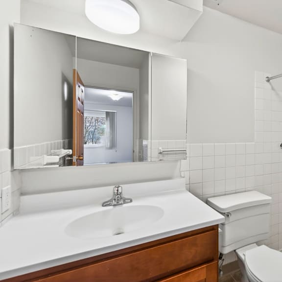 a white bathroom with a sink, toilet and shower.