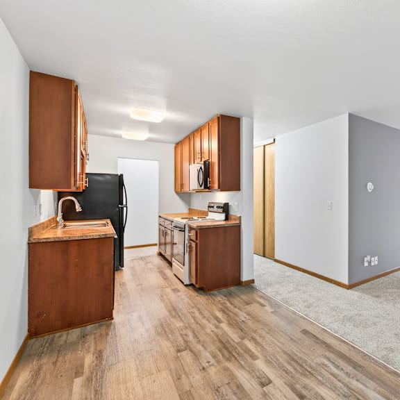 a room with wooden floors and a black refrigerator.