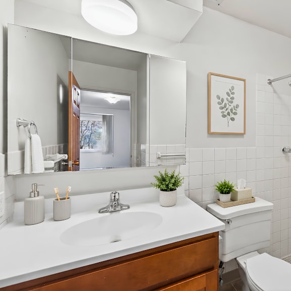 a white bathroom with a wooden vanity and a white toilet.