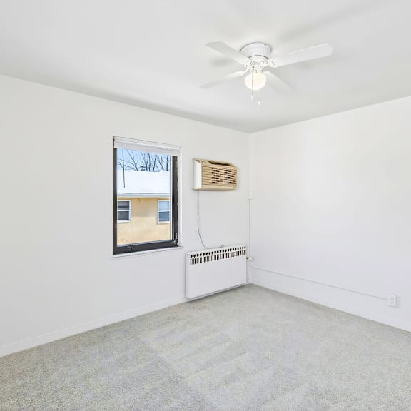 a room with a ceiling fan and a window.