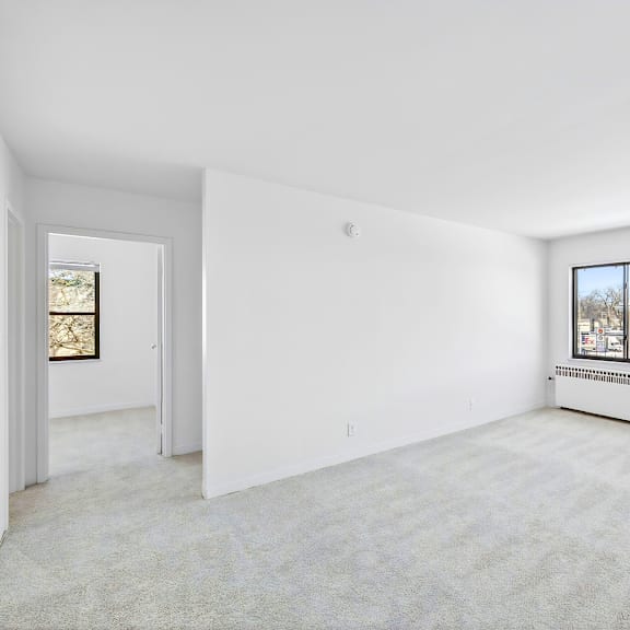 a large, empty room with a carpeted floor and a window showing a view of a street.