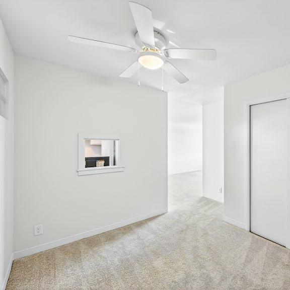 a room with a ceiling fan and a window with a picture frame on the wall.