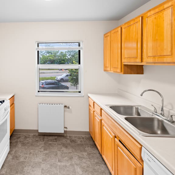 a kitchen with a white fridge, white stove, and a window with a view of the street.