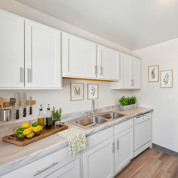 a kitchen with white cabinets and a wooden cutting board with lemons and herbs on it.
