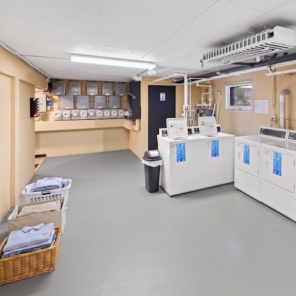 a room with two large white machines and a basket of towels on the left.