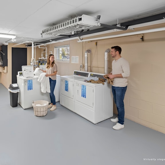 two people in a room with a large machine and a basket on the floor.
