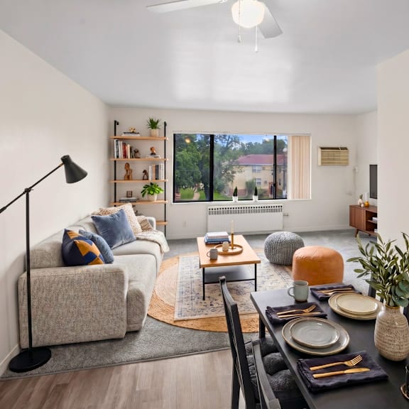 a well-lit living room with a dining table set for two.