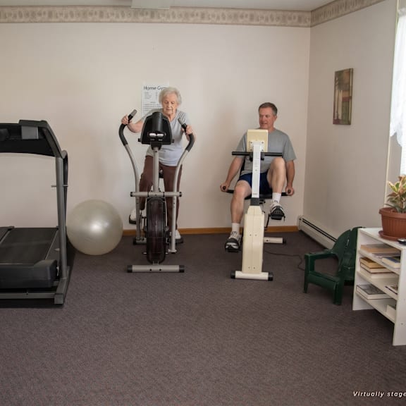 a man and a woman are exercising in a room with a treadmill, a stationary bike, and a rowing machine.