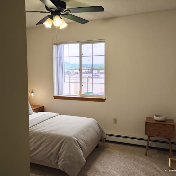 a bedroom with a bed, a nightstand, and a window.