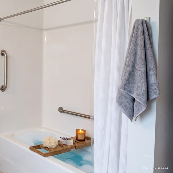 a bathroom with a white tub and a grey towel hanging on the shower rod.