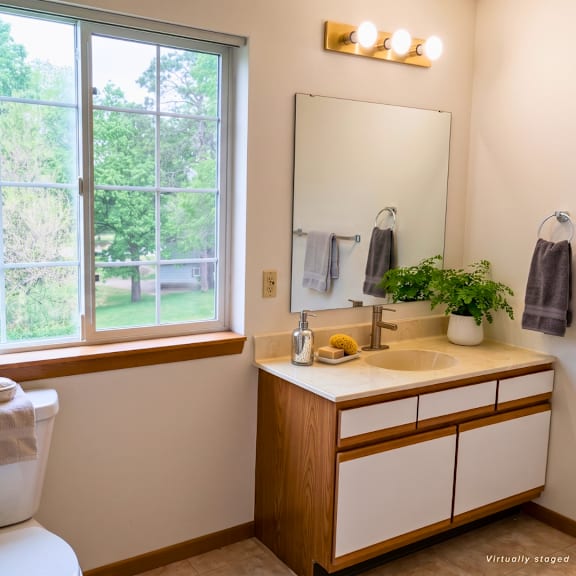 a bathroom with a toilet, sink, and a window.