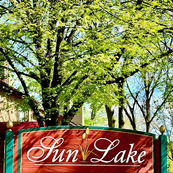 a sign that says sun lake in front of some trees.