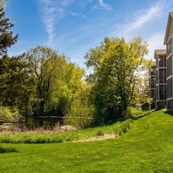 a serene landscape with a building on the right and trees in the background.