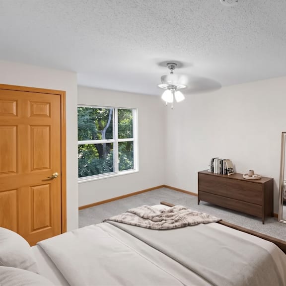 a bedroom with a bed, dresser, mirror, and chair.