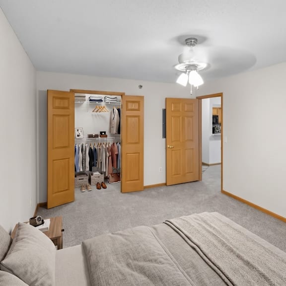 a bedroom with a grey carpet and two open doors.
