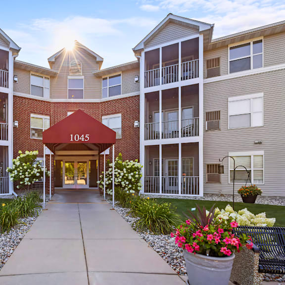 the image shows a beautiful day at the entrance of apartment building 1045 with a clear blue sky and sunlight shining through the windows.