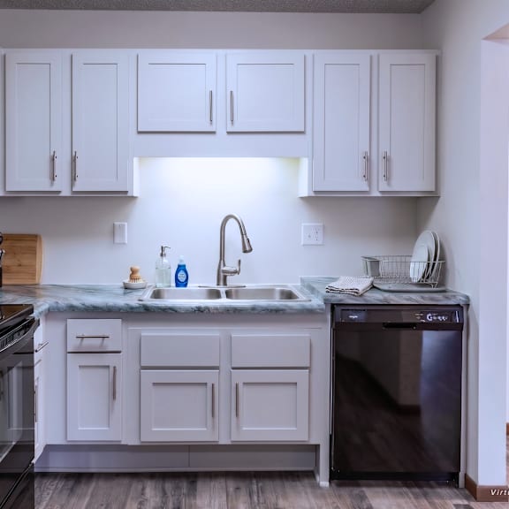 a kitchen with white cabinets and a black refrigerator.