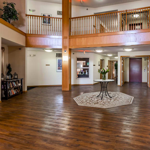 a large open space with a table and chairs in the foreground and a balcony in the background.
