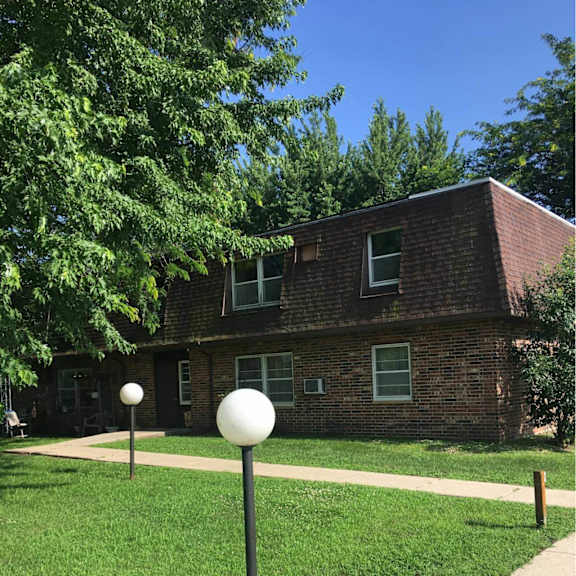 a white ball is on a pole in front of a brick house.