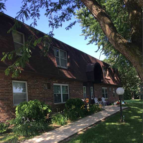 a red brick house with a white lawn chair on the front porch.