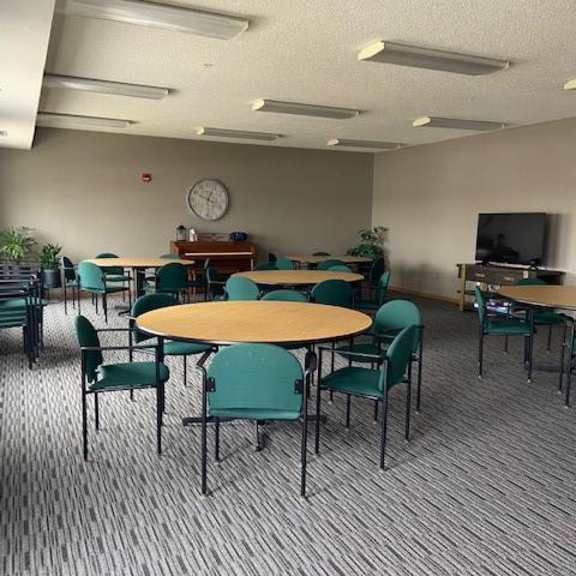 a room with tables and chairs and a clock on the wall.