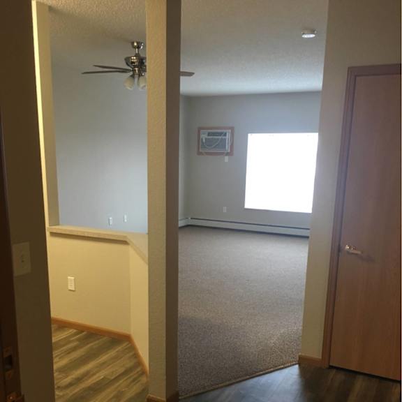 a hallway with a wooden floor and a ceiling fan.