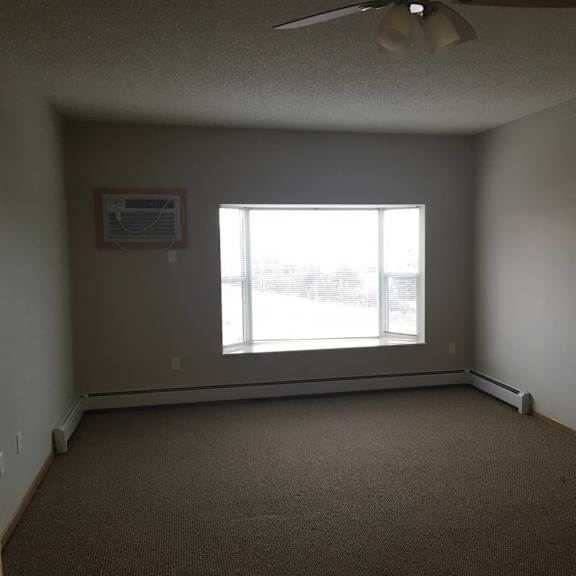 a room with a window and a fan on the ceiling.